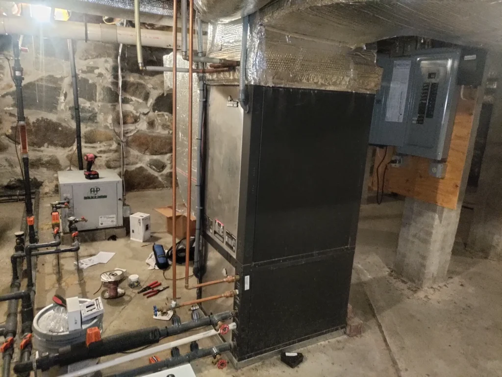 Geothermal heat pump with loop flow center installed in a basement