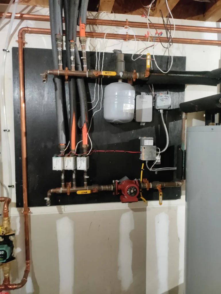 Geothermal system piping, pumps and manifold on a basement wall