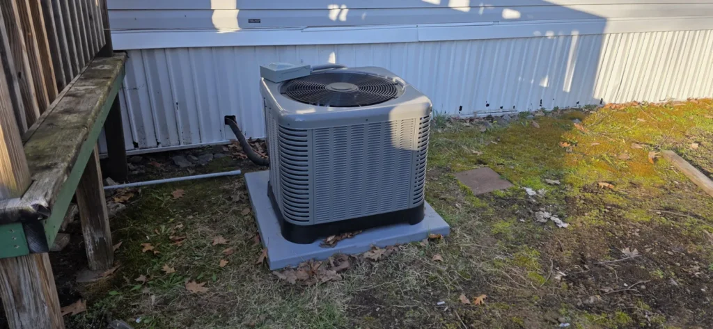 Air conditioning condenser on a level pad next to a lawn