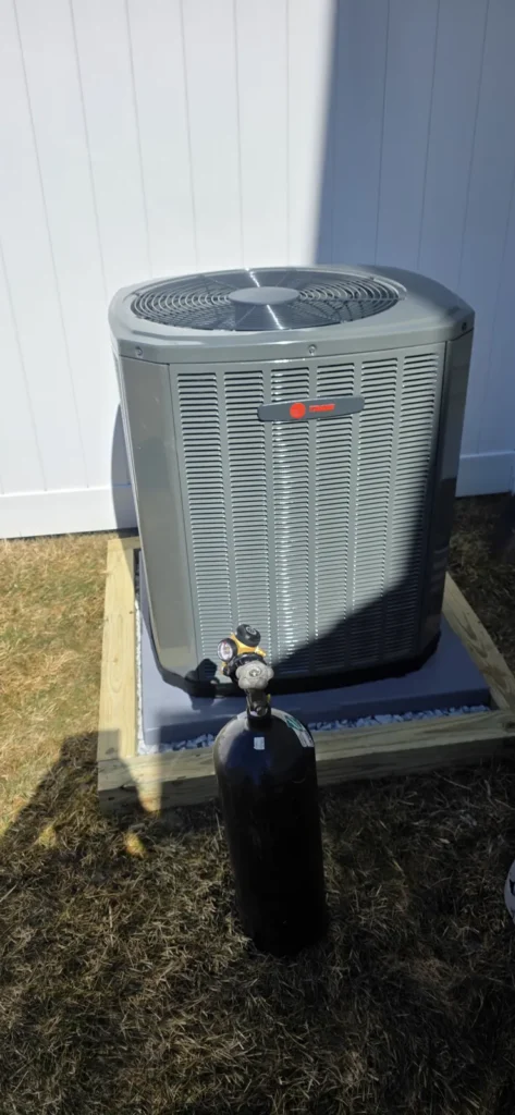 Air conditioner outdoor unit beside white siding