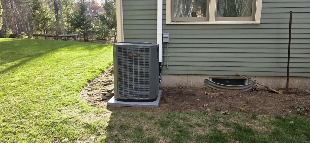 Central AC condenser beside a home with a green lawn