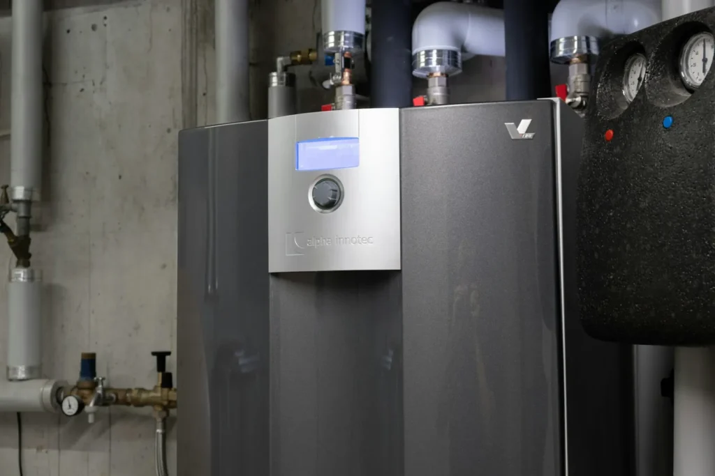 Close-up of an indoor geothermal heat pump unit with control panel and piping