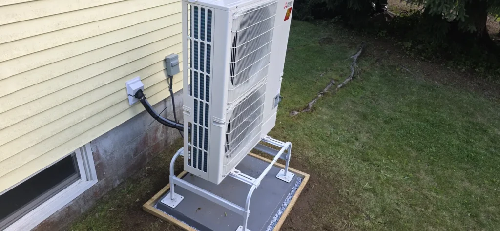 Air-source heat pump on a stand above snow level