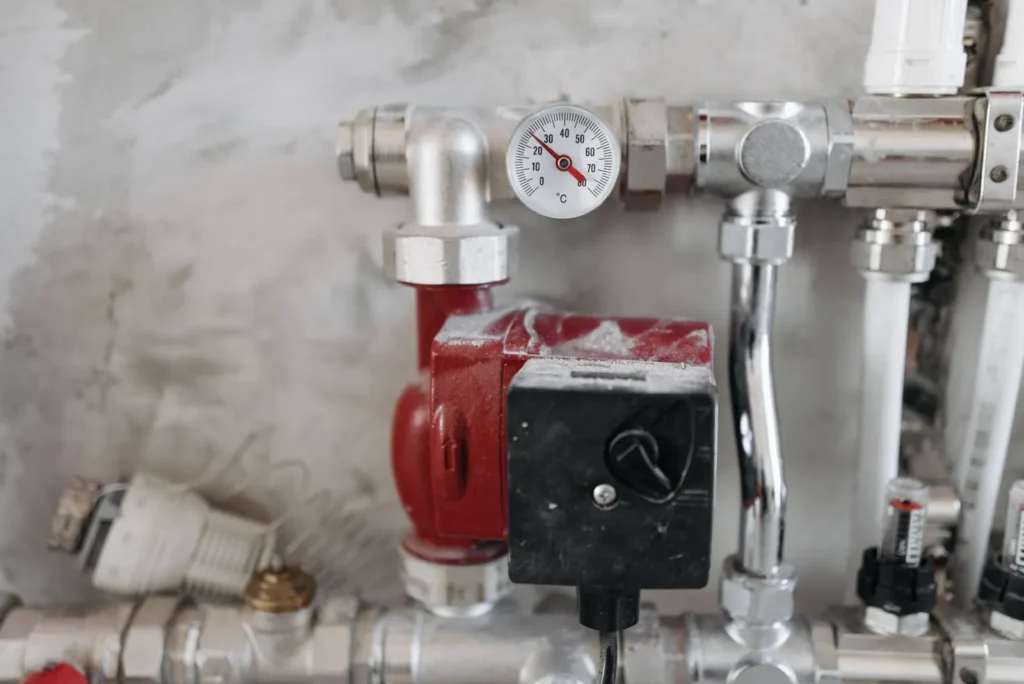Hydronic heating circulator pump and pressure gauge on a steel pipe manifold