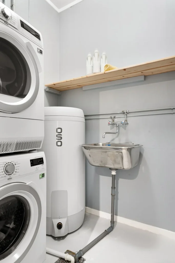 Tall tank water heater installed beside a stacked washer and dryer