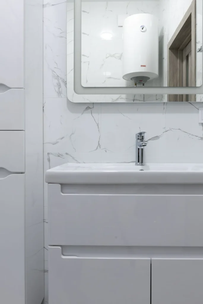 Electric water heater mounted on the wall above a white bathroom vanity
